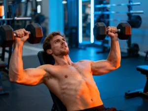 Skupiony mężczyzna wykonuje intensywny trening obwodowy z odważnikami kettlebell w nowoczesnej siłowni.